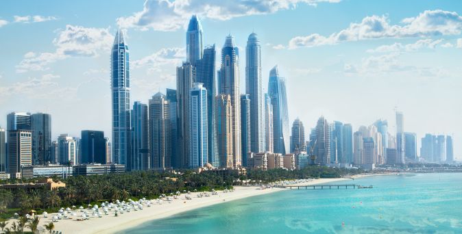 Skyline von Dubai Marina mit modernen Wolkenkratzern, türkisblauem Wasser und hellem Sandstrand an der Küste Dubais in den Vereinigten Arabischen Emiraten