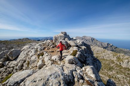 Wanderer auf dem Gipfel des Puig de Massanella, dem zweithöchsten Berg Mallorcas, mit weitem Blick über das Tramuntana-Gebirge