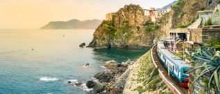Regionalzug am Bahnhof von Manarola in den Cinque Terre in Ligurien mit Felsklippen, Küstenbahnstrecke und Blick auf das Ligurische Meer