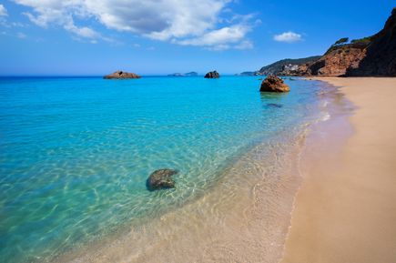 Strand Aguas Blancas mit goldgelbem Sand, Felsen und sanften Wellen
